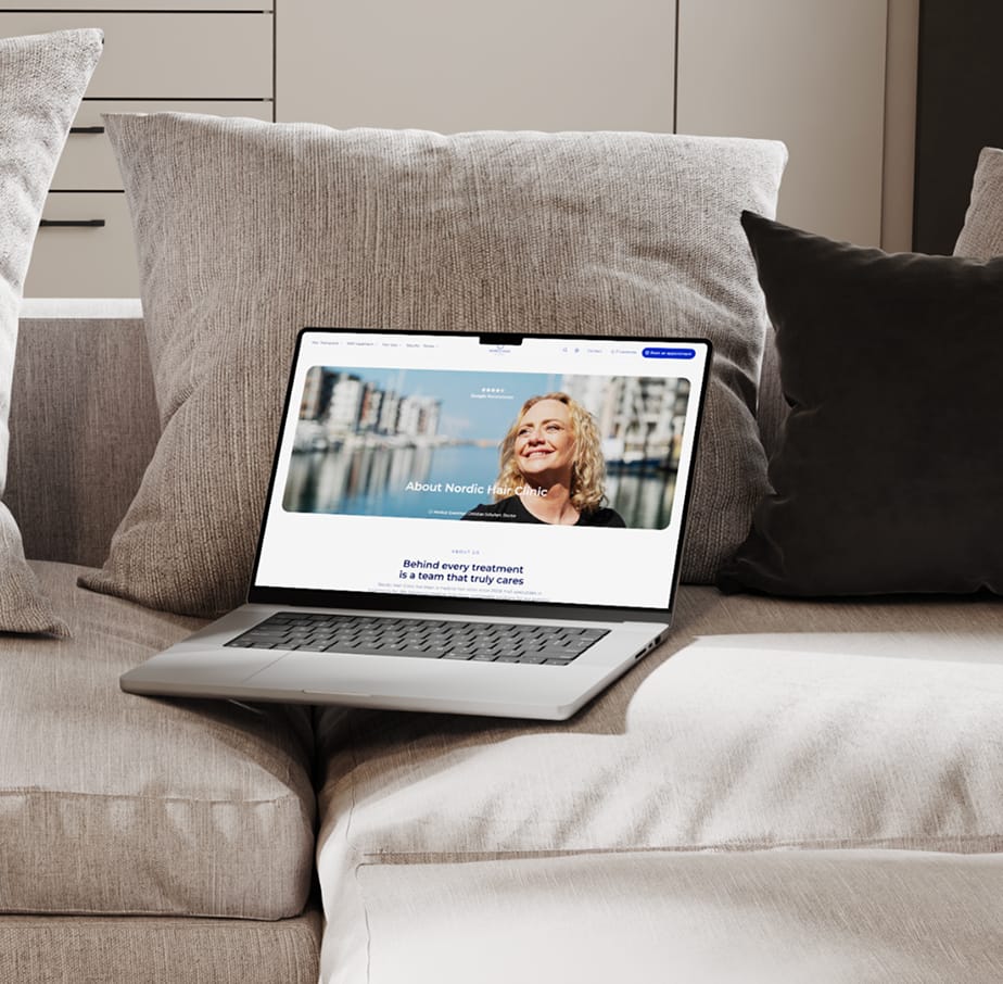 Laptop i en soffa som visar Nordic Hair Clinics om oss-sida